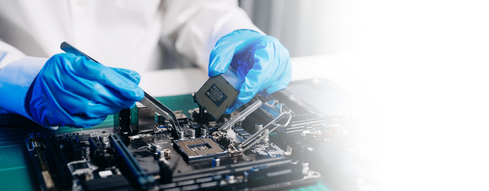 A technician in nitrile gloves handling a processor with tweezers at an inspection bench.
