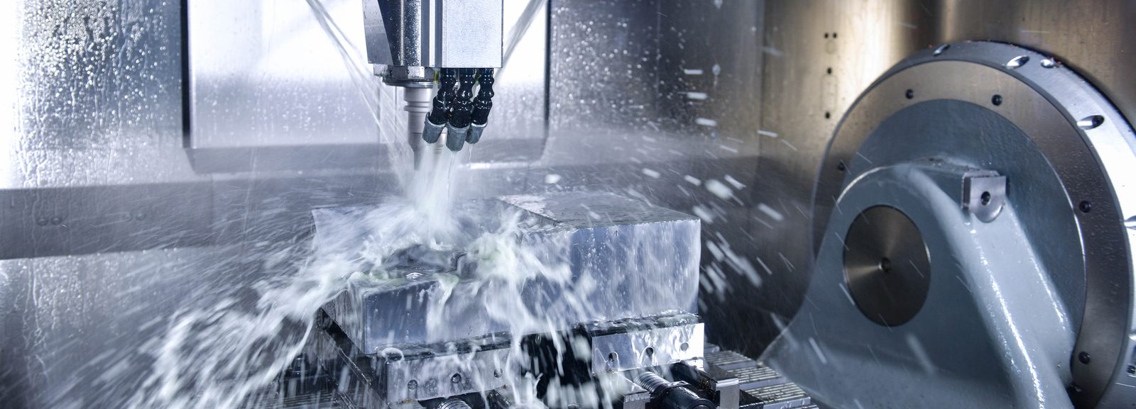 A machining centre cutting a workpiece under flooding coolant.