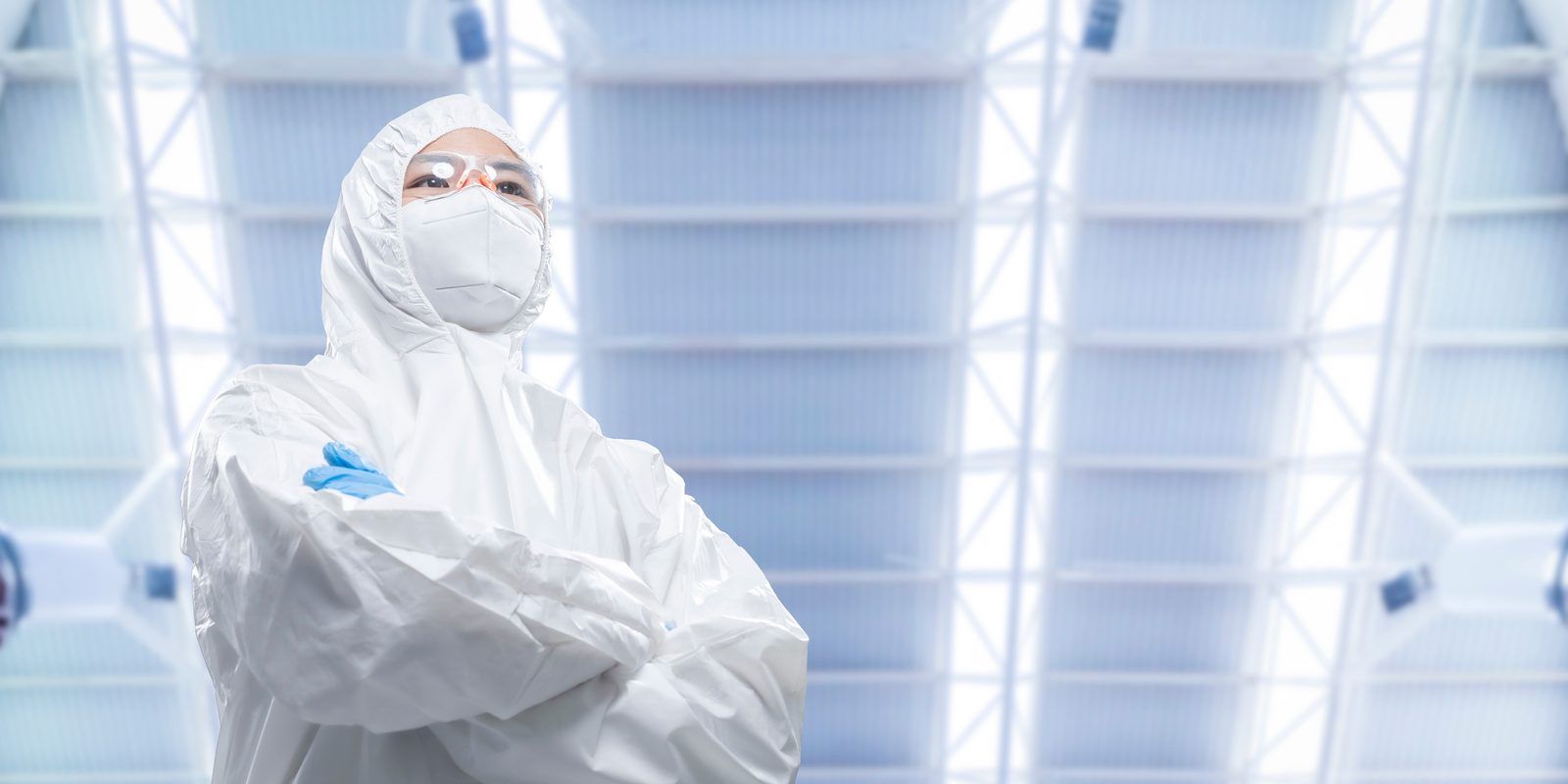 A technician in a cleanroom coverall, hood and mask standing in a filtered cleanroom bay.